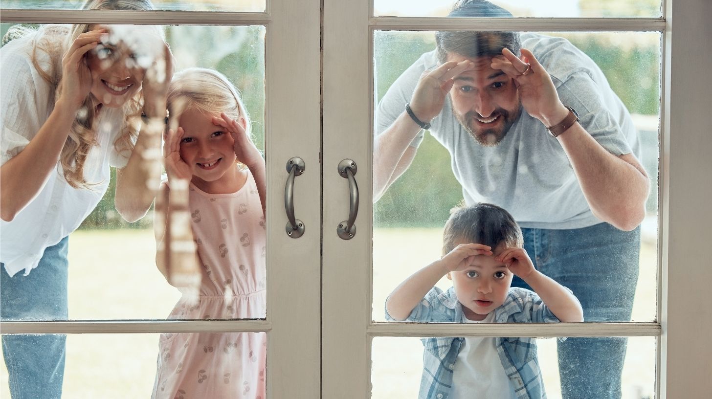 A family peering into their home through a glass door