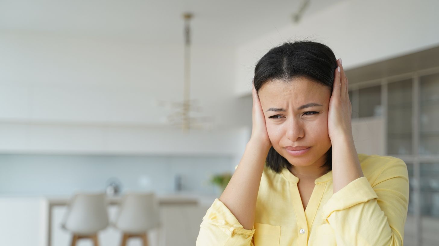 a woman covering her ears out of frustration from noise pollution a woman covering her ears out of frustration from noise pollution